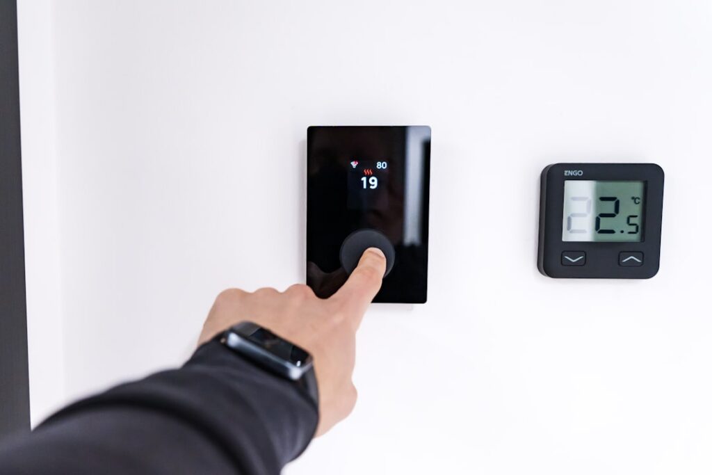 How Often Should You Service Your HVAC System? 2 HVAC system thermostat homeowner adjusting digital display home comfort
